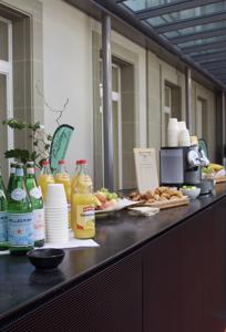 Ein schön gedecktes Pausenbuffet mit Mineralwasser, Orangensaft, Gipfeli, Brötchen, Früchten und einer Kaffeemaschine.
