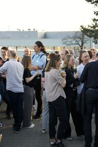 Menschen stehen auf einer Terrasse beieinander und sprechen miteinander.
