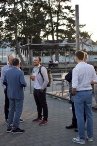 Menschen stehen auf einer Terrasse beieinander und sprechen miteinander.