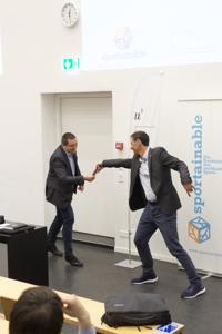 Ein Mann übergibt einen Staffettenstab sportlich an einen anderen Mann.
